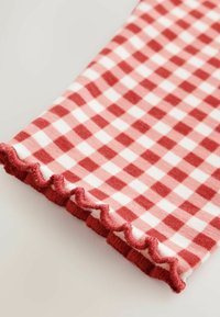 Primer plano de tela a cuadros roja y blanca con un borde ondulado.