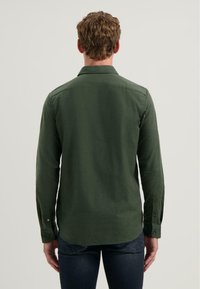 Groene lange mouwen shirt met een button-down kraag, met een gladde textuur en een rechte snit. Knopen op de manchetten zijn zichtbaar.