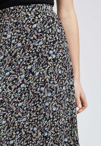 Jupe noire à motifs floraux, dotée d'une taille avec un élastique froncé, ornée de motifs floraux bleus, roses et jaunes sur un fond sombre.