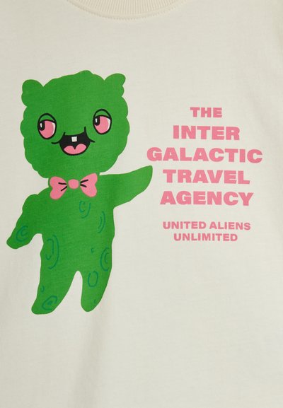 Πράσινος καρτουνίστικος εξωγήινος με ροζ παπιγιόν που δείχνει προς τα δεξιά, δίπλα σε ροζ κείμενο: «Η Διαγαλαξιακή Ταξιδιωτική Υπηρεσία Ενωμένοι Εξωγήινοι Απεριόριστα.»