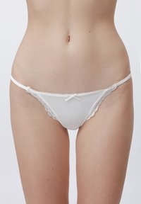 Witte kant afgewerkte thong met doorschijnende stof, voorzien van een centraal strikdetail en dunne zijkanten, ontworpen voor een minimalistische uitstraling.