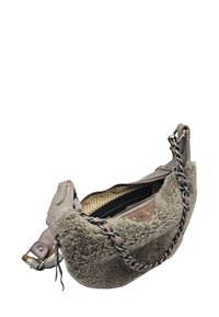 Sac gris en fausse peau de mouton avec une bandoulière chaîne tressée, doté d'une fermeture éclair et d'un intérieur à motif floral jaune.