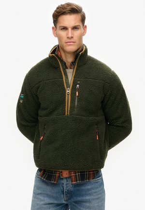 Groene fleece pullover met een hoge kraag, kwart rits en een gestructureerd oppervlak. Beschikt over twee ritszakken en contrasterende tan rand.