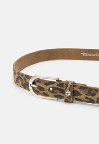 Hnědo-černý opasek s leopardím vzorem vyrobený z kůže, s kovovou sponou a bezpečnou smyčkou s akcentovým nýtem. Viditelné detaily texturovaného povrchu.
