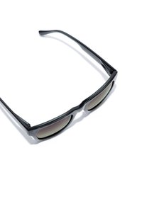 Černé sluneční brýle s elegantním, zaobleným designem. Čočky jsou tónované šedým gradientem s lesklými akcenty na stranicích.