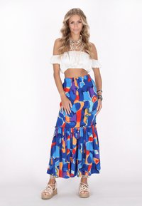 Vállnélküli, fehér crop top, amely egy színes, kék, narancssárga és piros mintás maxi szoknyával van párosítva, fodros aljjal és elasztikus derékkal.