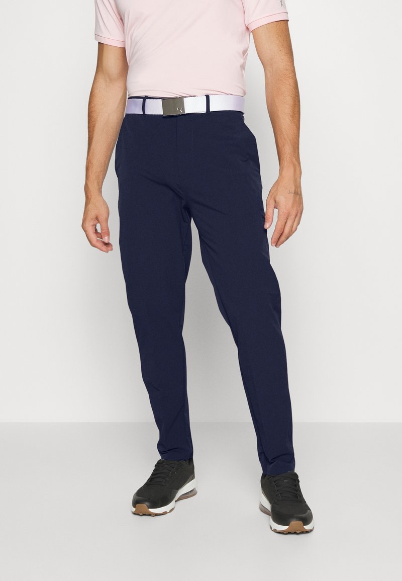 Marina blå träningsbyxor med smal passform, stretchigt tyg, elastisk midja och ett kontrasterande vitt bälte med ett silverfärgat spänne.