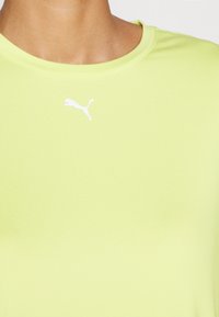 Limeta zelena kratka sportska majica s glatkim materijalom, okruglim izrezom i bijelim Puma logotipom na prsima.
