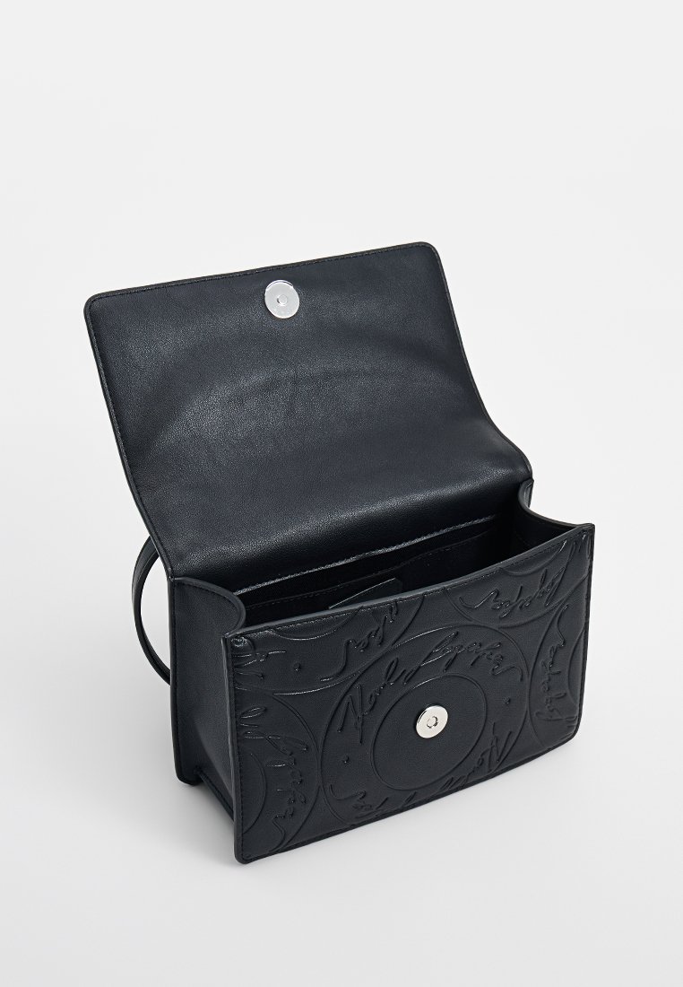 Borsa a tracolla in pelle nera con motivi circolari in rilievo, flap aperto, chiusura magnetica argentata e tracolla regolabile visibile all'interno.