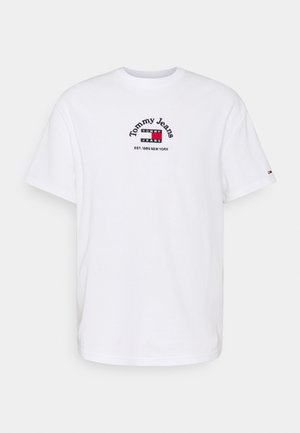 White short-sleeve crew neck T-shirt with "Tommy Jeans" logo, red, white, and blue flag graphic, and "EST. 1985 NEW YORK" text on front center.