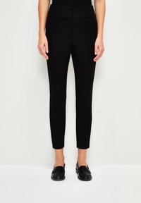Zwarte slim-fit broek met een gladde textuur en een hoge tailleband, voorzien van een taps toelopend beenontwerp, gecombineerd met zwarte instappers.