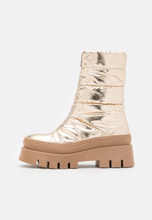 Bottines métalliques dorées avec un design gonflé, fermeture éclair latérale et une semelle plateforme chunky beige avec des bords crantés.