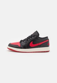 Sneaker in pelle nera con accenti rossi, dotato di una tomaia perforata, collo imbottito e suola intermedia bianca con suola in gomma rossa.