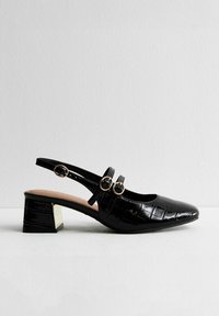 Svart lackläder slingback-sko med fyrkantig tå, två spännen och en texturerad yta i en design med låg klack.