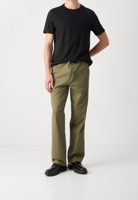 Sort kortærmet t-shirt, olivengrøn lige ben bukser, sorte sko. Bukserne har en glat tekstur og standard taljedesign.