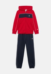 Κόκκινο φούτερ με φερμουάρ και ναυτικά στοιχεία· διαθέτει κουκούλα, μπροστινές τσέπες και λευκή ρίγα. Συνδυάζεται με ναυτικό παντελόνι jogger με ριμπ μανσέτες.