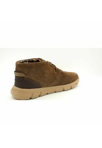 Stivaletti alla caviglia in suede marrone con finitura testurizzata, suola in gomma beige e dettagli in pelle marrone. Presentano una fodera interna con motivo.
