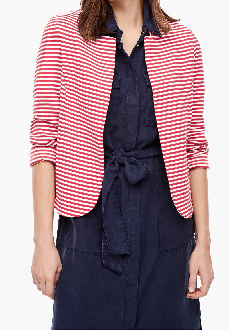 Rood-witte gestreepte blazer met een ronde kraag, driekwart mouwen en een getailleerde pasvorm, gedragen over een donkerblauwe jurk met een strikceintuur.