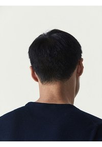 Kortærmet, tekstureret navy sweater med ribbet halsudskæring, set bagfra, der viser et enkelt og rent design.