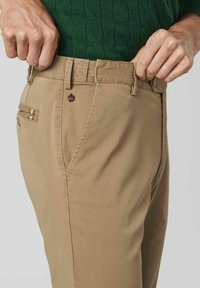 Khaki pants made of cotton, featuring a straight-leg design, visible pockets, and a subtle texture. Includes a button closure with a logo.
