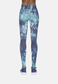 Legginsy z wysokim stanem z nadrukiem galaktyki w odcieniach niebieskiego i zielonego. Wykonane z elastycznego materiału o gładkiej fakturze, zaprojektowane dla komfortu.