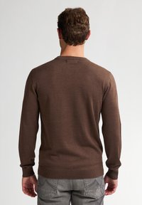 Suéter marrón de manga larga con cuello redondo, hecho de un material de punto suave, que cuenta con puños y dobladillo acanalados para un ajuste ceñido.