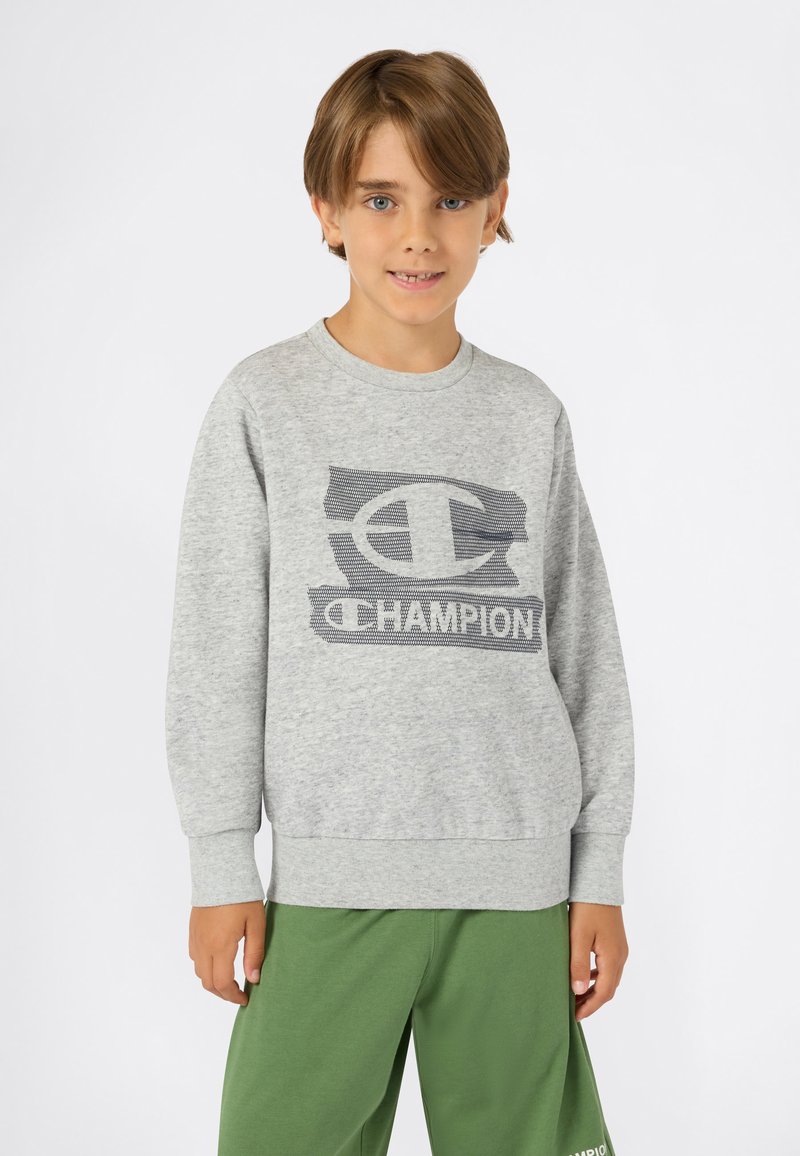 Felpa grigia con logo "Champion" testurizzato, scollatura rotonda e polsini a coste, abbinata a pantaloni della tuta verdi. Tessuto morbido e casual.