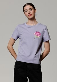 Lichtpaarse katoenen T-shirt met korte mouwen en een ronde hals, met een roze lotusbloemontwerp op de linker borst.