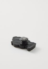 Pince à cheveux noire en forme de nuage avec un bord texturé. Présente un dessus rond avec un logo. Le matériau semble brillant, au design compact.