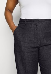 Donkerdenim broek met een gladde textuur, een klassieke pasvorm, voorzakken, een taille met riemlussen en een strakke, op maat gemaakte uitstraling.
