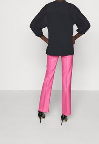Svart topp med puffärmar, parat med knallrosa, åtsittande byxor. Outfiten kompletteras av svarta stilettklackar.