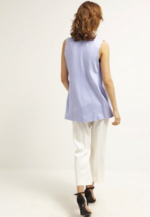Haut sans manches bleu clair avec une coupe droite, associé à un pantalon blanc et des chaussures à talons noirs. Tissu lisse et lignes épurées.