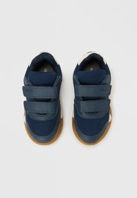 Σκούρα μπλε αθλητικά παπούτσια από δίχτ�υ και δέρμα, με δύο λουριά Velcro, σόλα από καουτσούκ χρώματος καραμέλας και λευκές λεπτομέρειες στα πλάγια.