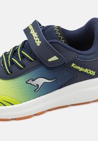 Sportschoen met een bovenwerk van net in marineblauw, groen en geel. Voorzien van een klittenbandsluiting, rubberen zool en een kangoeroe-logo. Textuuraccenten verbeteren de grip.