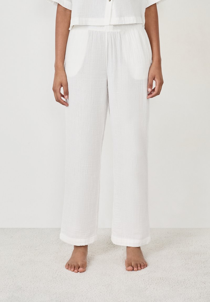 Witte, loszittende broek van lichtgewicht stof met een gekreukeld textuur. Heeft een elastische tailleband en opgerolde zoom.
