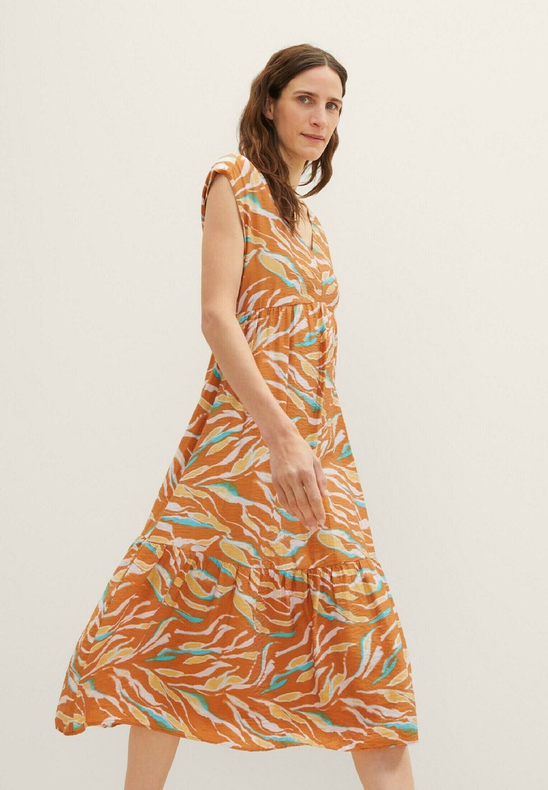 Braun gemustertes Kleid mit einem lockeren, gestuften Design, kurzen Ärmeln und mehrfarbigen gewellten Linien in Blau und Weiß.