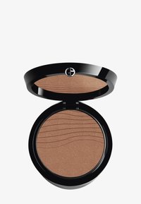 Bronzer in einem schwarzen runden Kompakt mit einer glatten, warmbraunen Puderoberfläche, die Wellenmuster aufweist. Lässt sich mit einem eleganten Scharnier öffnen.