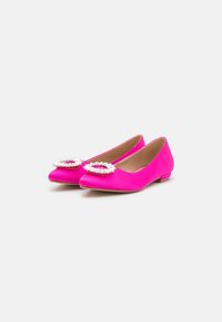 Zapatos planos fucsias hechos de material suave, con un acento decorativo de cuentas transparentes en el área de los dedos y una suela de perfil bajo.