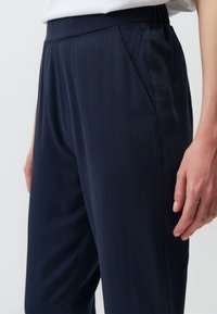 Navyblauwe broek van gladde stof, met een relaxed fit, een elastische tailleband en zijzakken met minimale stikseldetails.