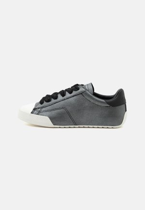 Γκρι δερμάτινο sneaker χαμηλής κοπής με μαύρα κορδόνια, λευκή λαστιχένια μύτη και μαύρη ένθετη φτέρνα, εμφανίζεται από το πλάι πάνω σε λευκό φόντο.