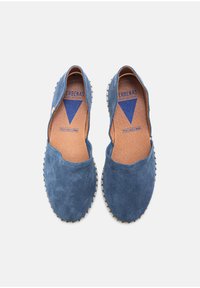 Blue suede flat shoes with a round toe, stitched beige accent around the sole, and a tan leather insole featuring a blue logo.
