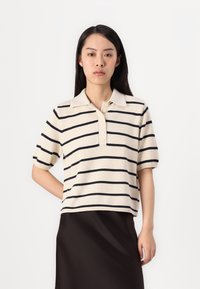 Kortärmad polo skjorta i beige med marinblå horisontella ränder, med krage och framknäppning, tillverkad av mjukt texturerat stickat material.