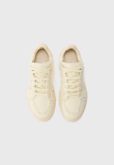 Canvas sneakers i lys gul, med flossede kanter, rund tå, flade snørebånd og en struktureret gummisål. Overdelen har en glat finish.