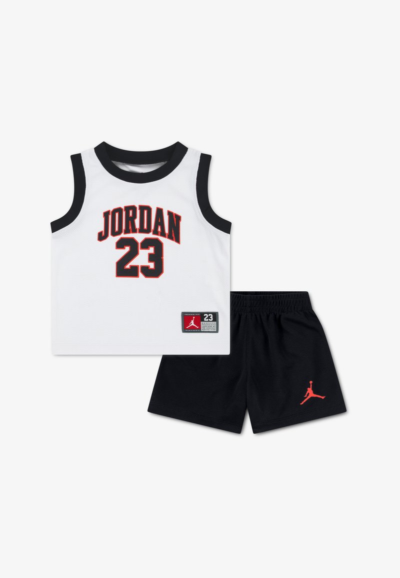 Valge võrgust tanktop musta äärisega, millel on punased sõnad „JORDAN“ ja number „23“. Mustad püksid punaste detailide ja logomärgiga.