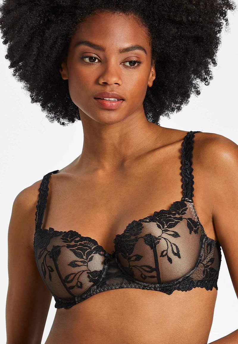 Soutien-gorge en dentelle noire avec broderies florales, bonnets transparents, bords festonnés et bretelles réglables. Motif floral texturé sur l'ensemble.