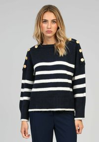 Pull rayé bleu marine et blanc avec ourlet côtelé, ornés de boutons dorés aux épaules et d'une coupe décontractée. Fabriqué en matériau tricot doux.