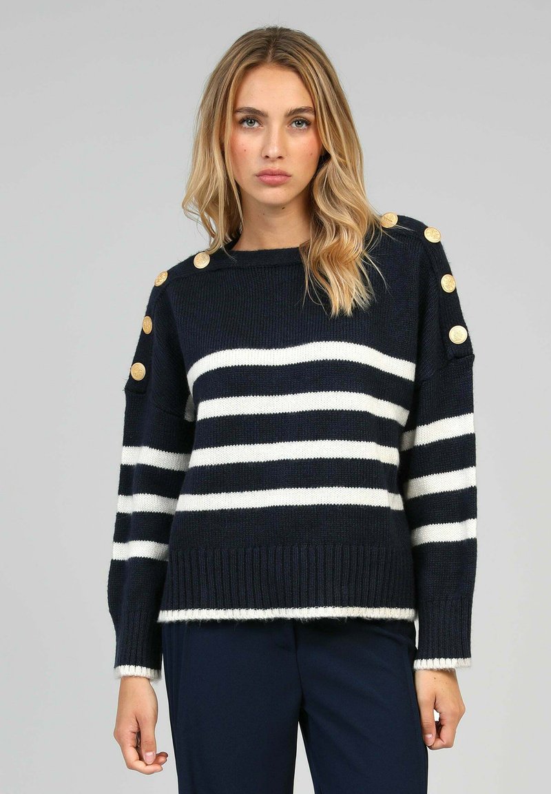 Pull rayé bleu marine et blanc avec ourlet côtelé, ornés de boutons dorés aux épaules et d'une coupe décontractée. Fabriqué en matériau tricot doux.