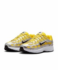 Nike-Laufschuhe mit einer Kombination aus leuchtend gelbem Mesh und reflektierendem Silbermaterial, schwarzen Akzenten und strukturiertem Außensohlen.
