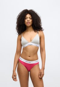 Sivá braletka s tenkými ramienkami a bielym pásom s logom, doplnená ružovými hipsterskými nohavičkami s bielym pásom s logom. Hladká textúra látky.