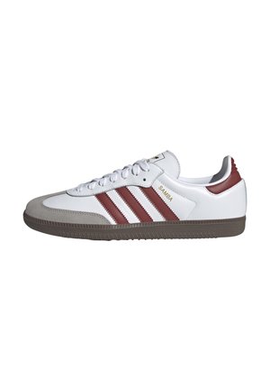 Bílá nízká teniska Adidas Samba s vínovými pruhy, šedým semišovým špičkovým dílem, hnědou podrážkou a tkaničkami na bílém pozadí.